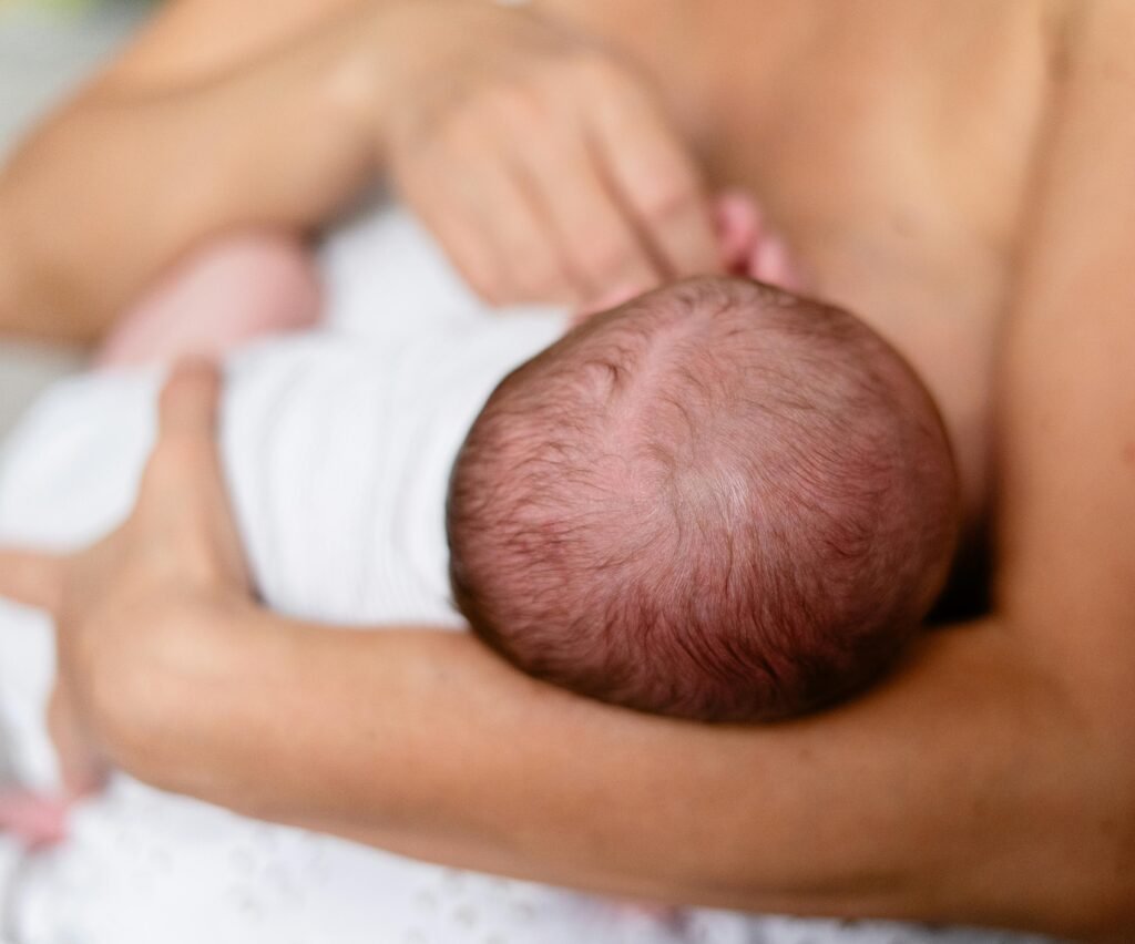 Mother breastfeeding her newborn, practicing latch and positioning